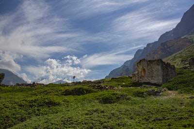 白天白云和蓝天下棕色岩层附近的绿色草地
